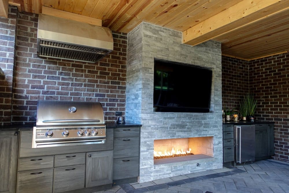 An outdoor kitchen with a fireplace and tv.